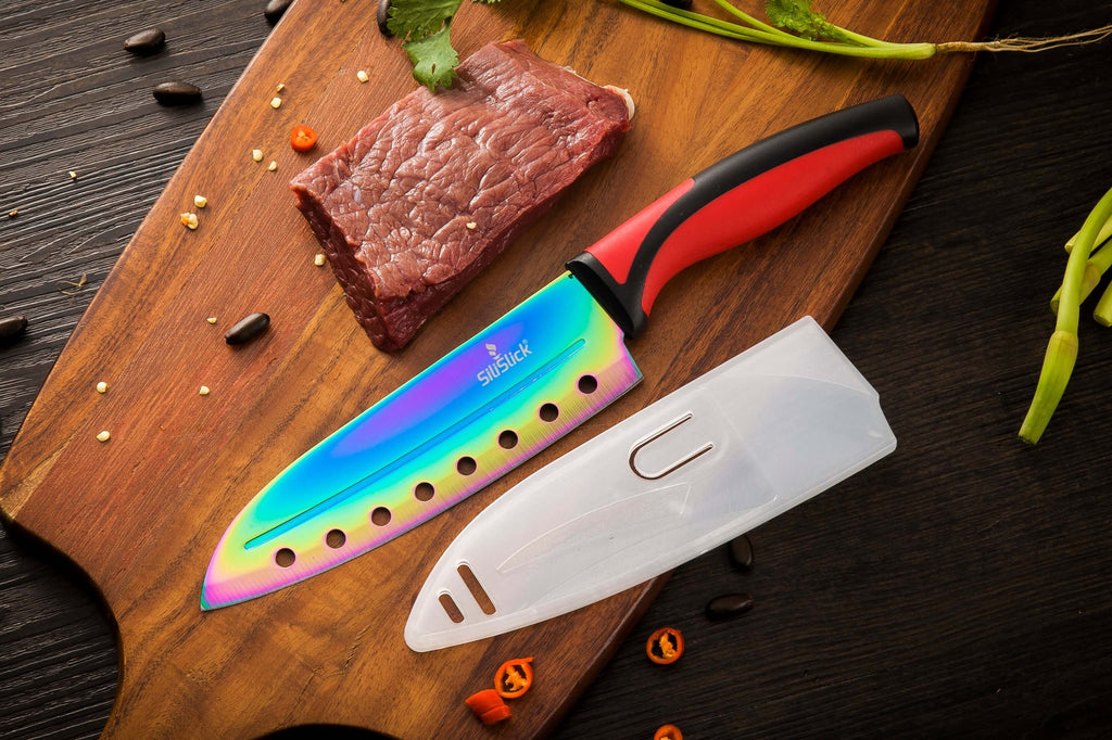 Chef's knife with a colorful blade on a wooden cutting board with raw meat.